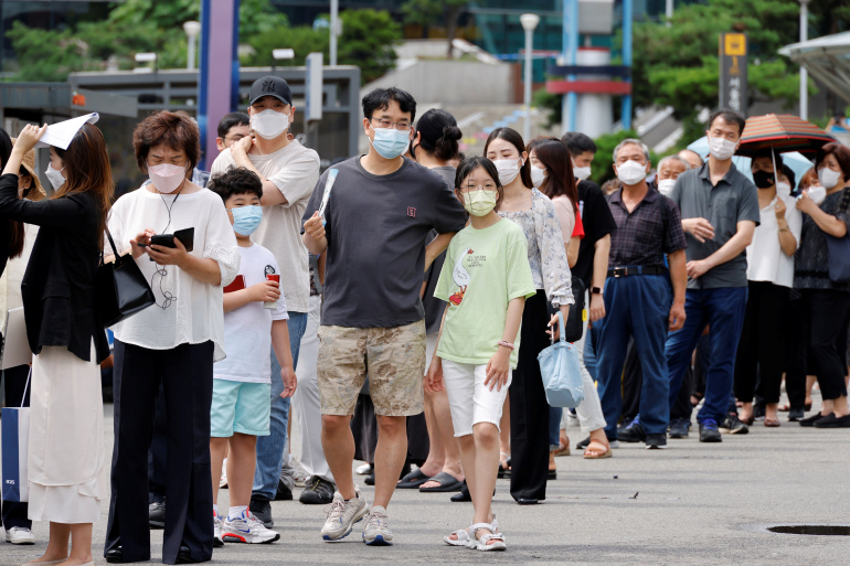People wait in line for a coronavirus disease (COVID-19) test at a testing site which is temporarily set up at a railway station in Seoul
